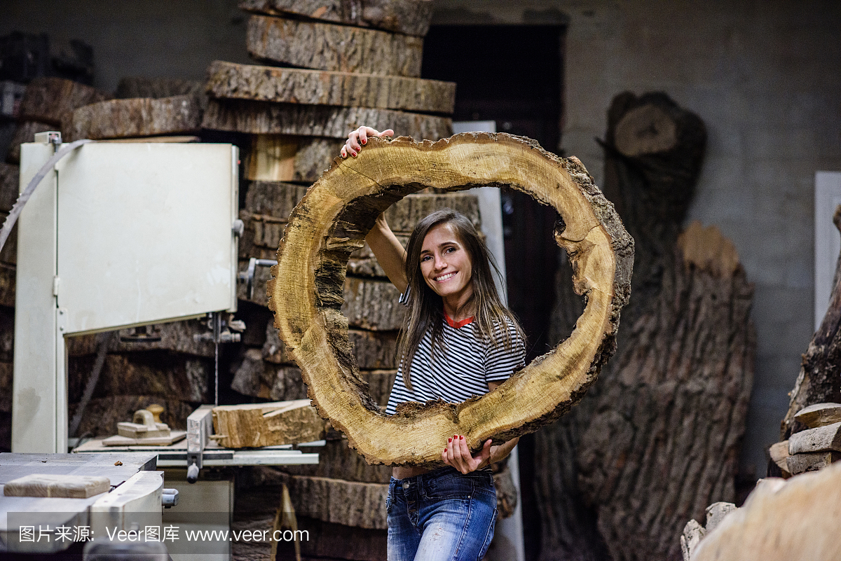 木工车间。年轻女子用木圆锯切产品。